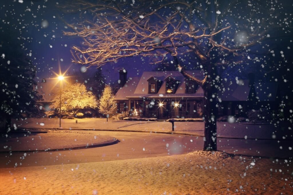 Snow falling at dusk on a quiet street with a lit house and lamps