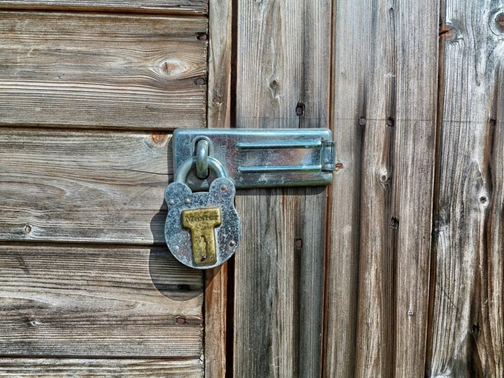 Rustic wooden door secured with a metal padlock and latch, symbolizing security and protection