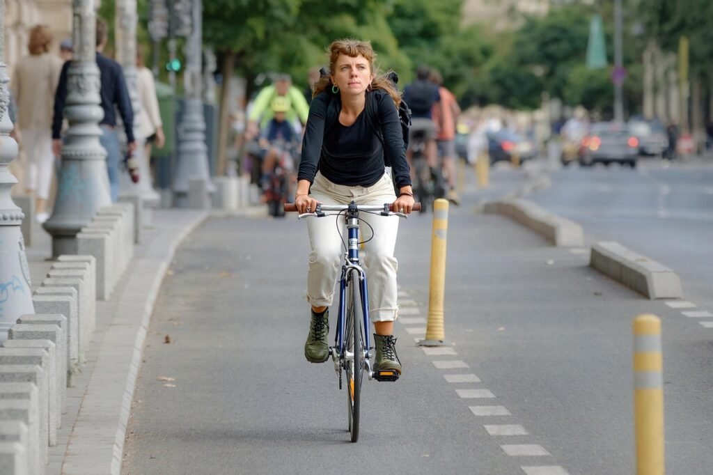 Woman riding a city bike down a marked bike lane beside yellow bollards