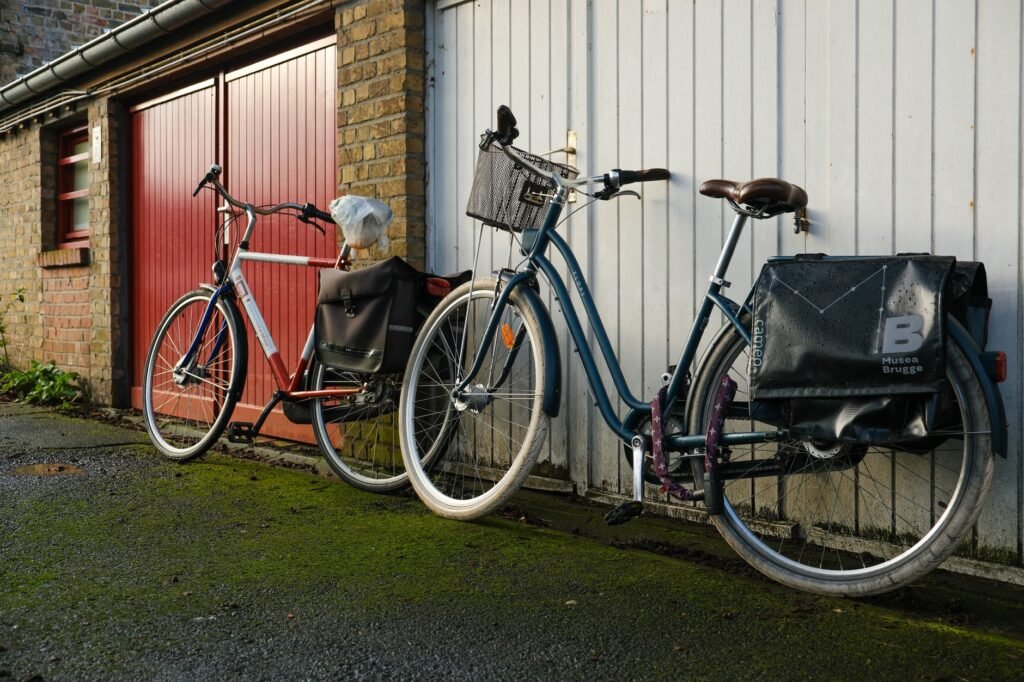 Two city bicycles with rear pannier bags leaning against a garage wall