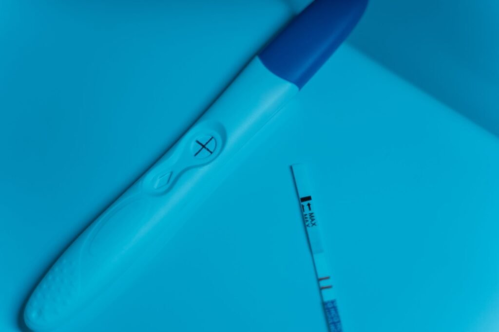 Home test stick and a thin test strip lying on a bright blue surface