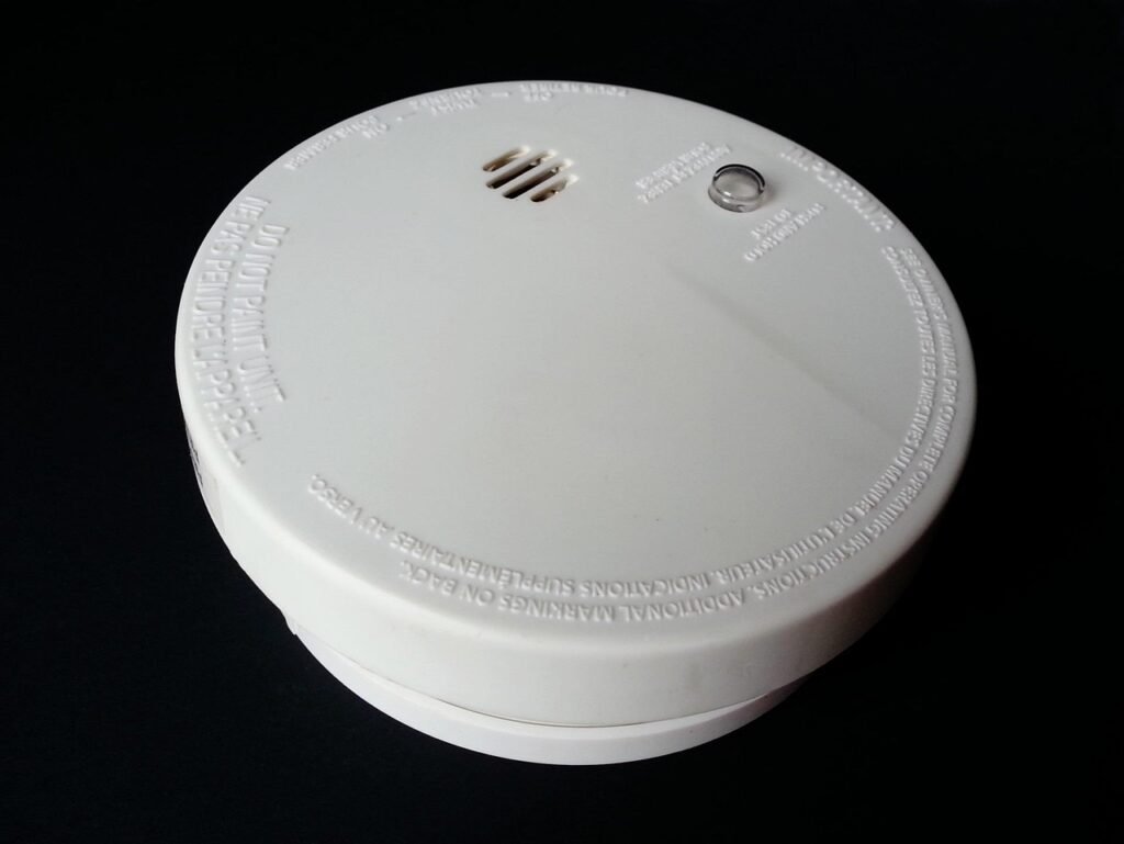 White round smoke detector with a test button against a black background