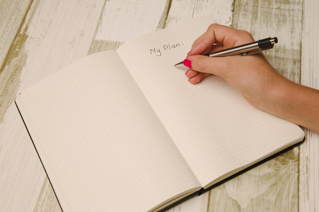Hand writing with a pen on the first page of an open grid notebook