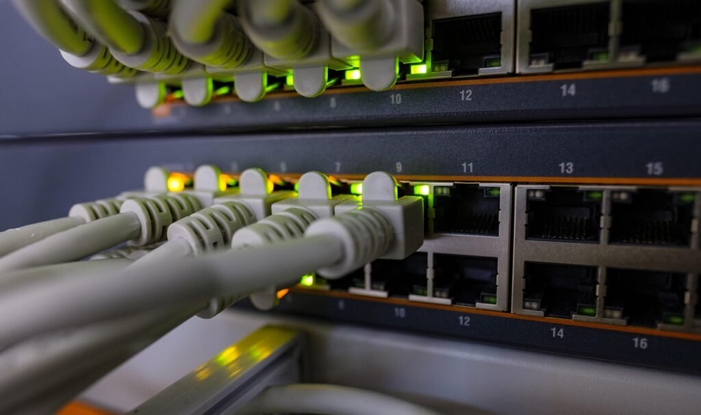 Gray ethernet cables plugged into a network switch with small green status lights
