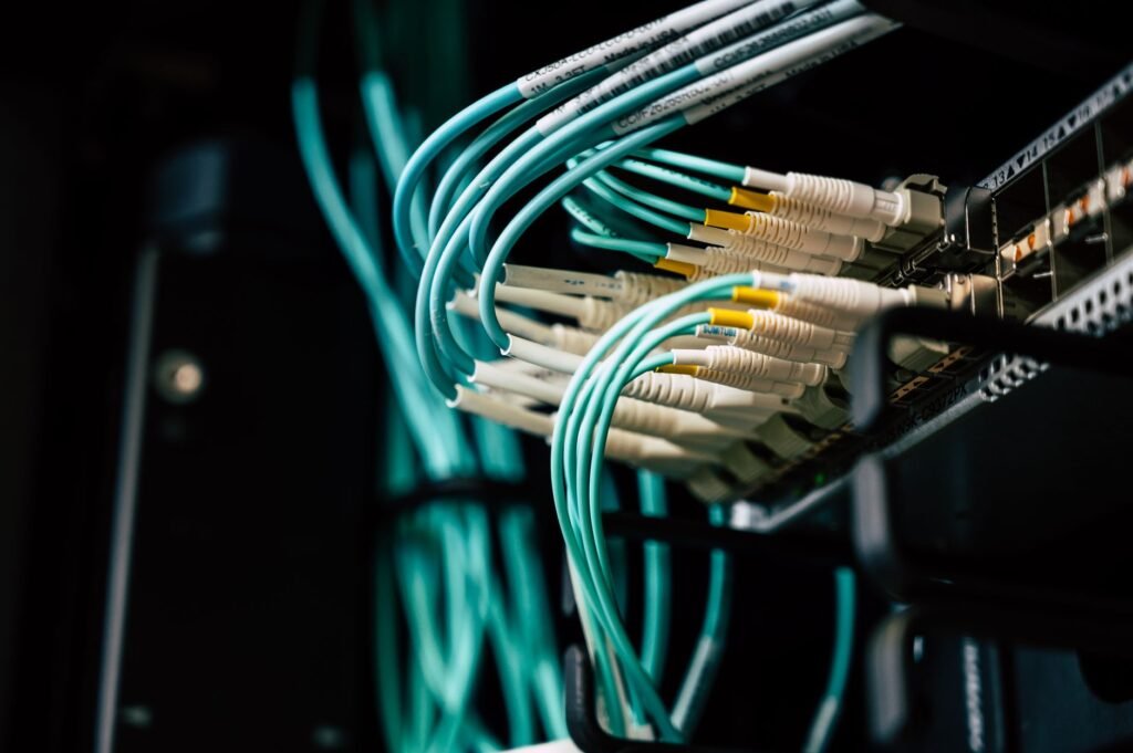 Blue network cables with white connectors plugged into a patch panel inside a dark server rack
