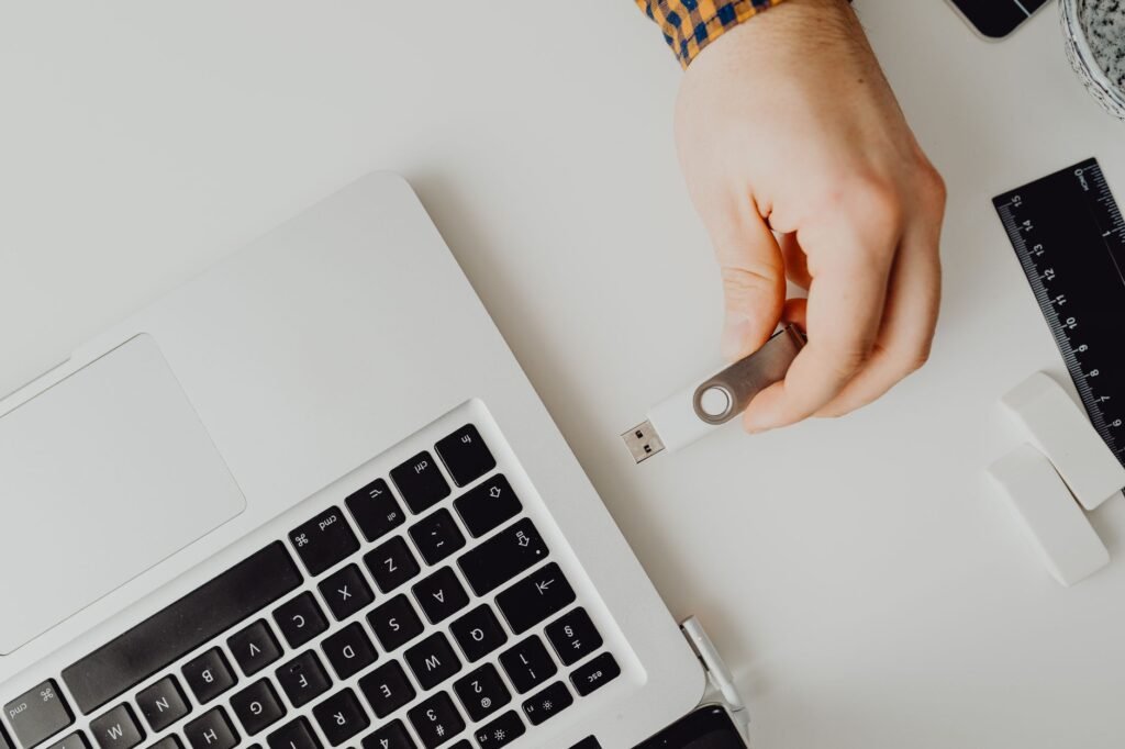 Hand inserting USB drive into laptop. Modern tech connection concept