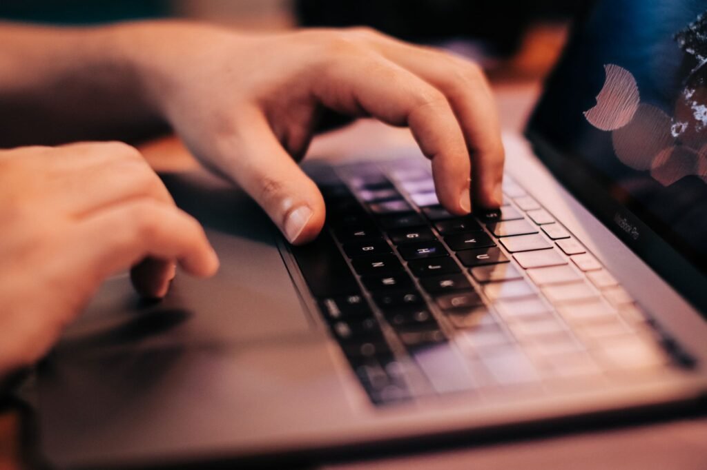 A person typing on a laptop with focus on hands and keyboard