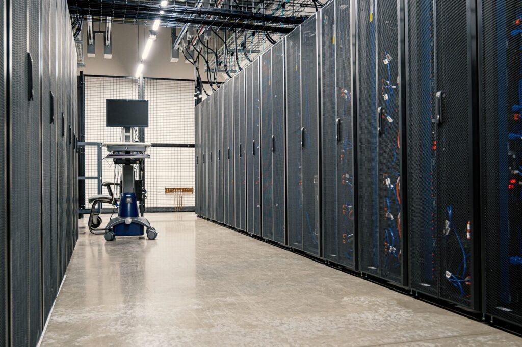 Long aisle between rows of black server racks in a bright data center
