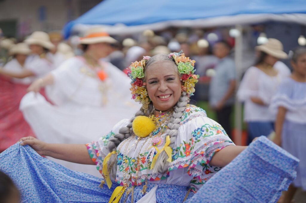 Smiling folk dancer with a flower headdress spreading her wide blue ruffled skirt at a festival