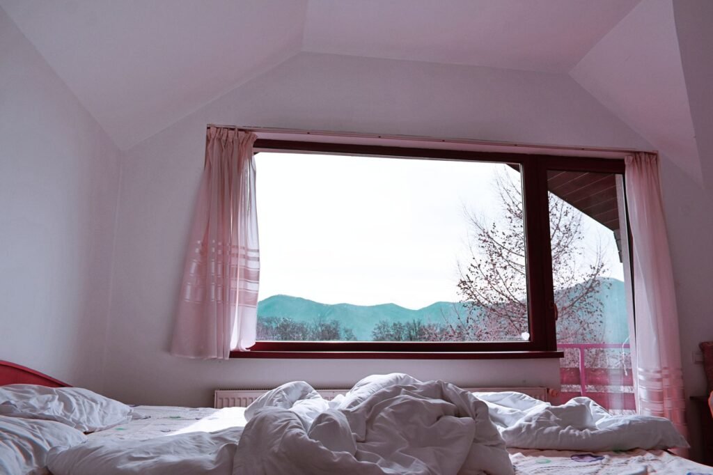 Bright bedroom interior with rumpled bed facing mountain view from window
