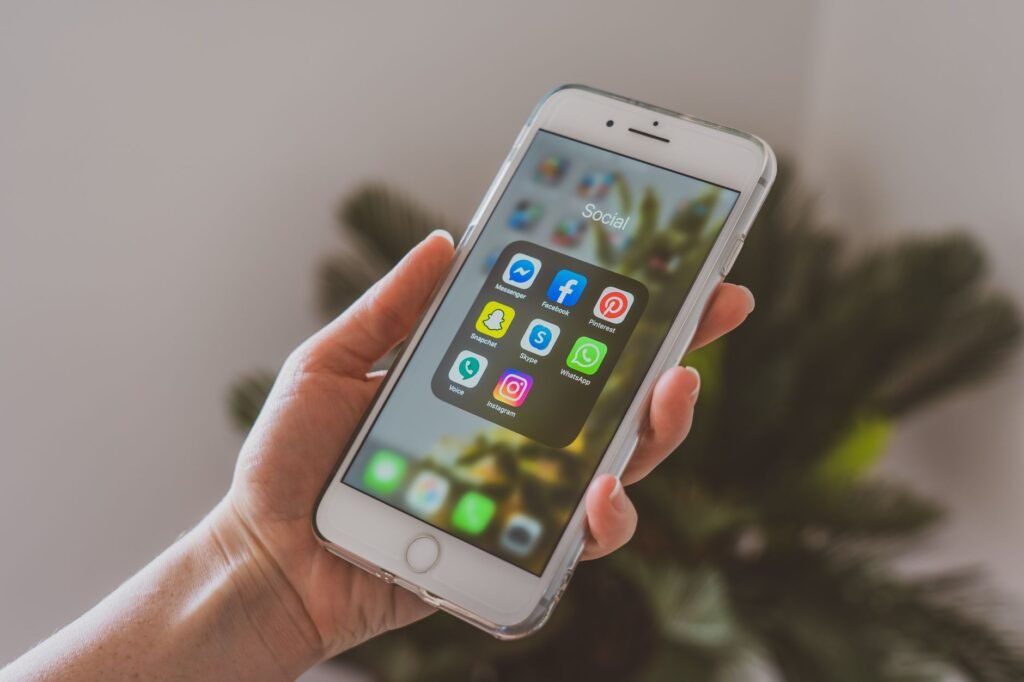 Close-up of a hand holding a smartphone displaying popular social media apps